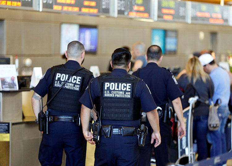 Officers with the U.S. Customs and Border Protection walk past ticket counters.