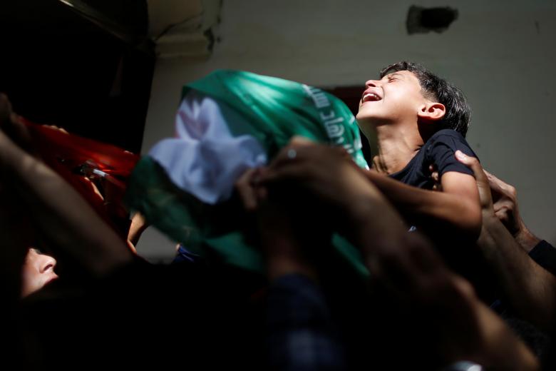 The brother of Palestinian man Ahmed Al-Shenbari, who was killed amid a flare-up of Israeli-Palestinian violence, reacts as mourners carry his body during his funeral in the northern Gaza Strip, May 11. Photo: Mohammed Salem/Reuters