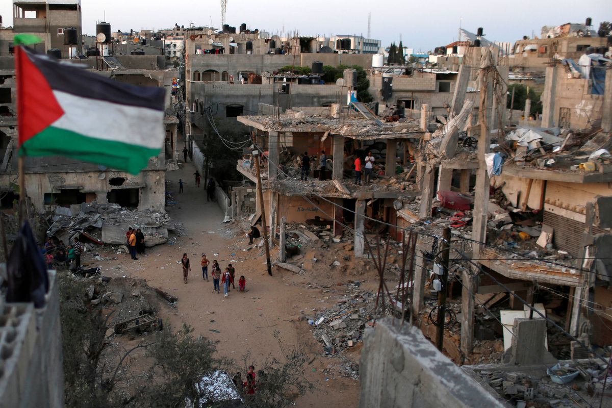 A Palestinian flag flies as the ruins of houses, which were destroyed by Israeli air strikes, are seen, in Gaza Strip, May 25. Photo: Mohammed Salem/Reuters
