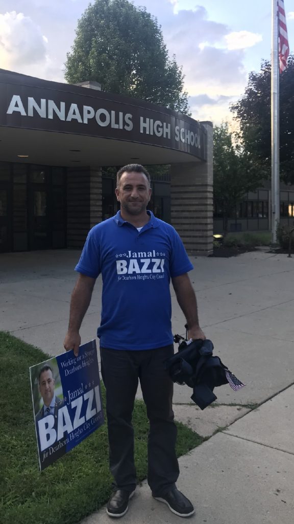 Candidate Jamal Bazzi holding a campaign sign at Annapolis High School.