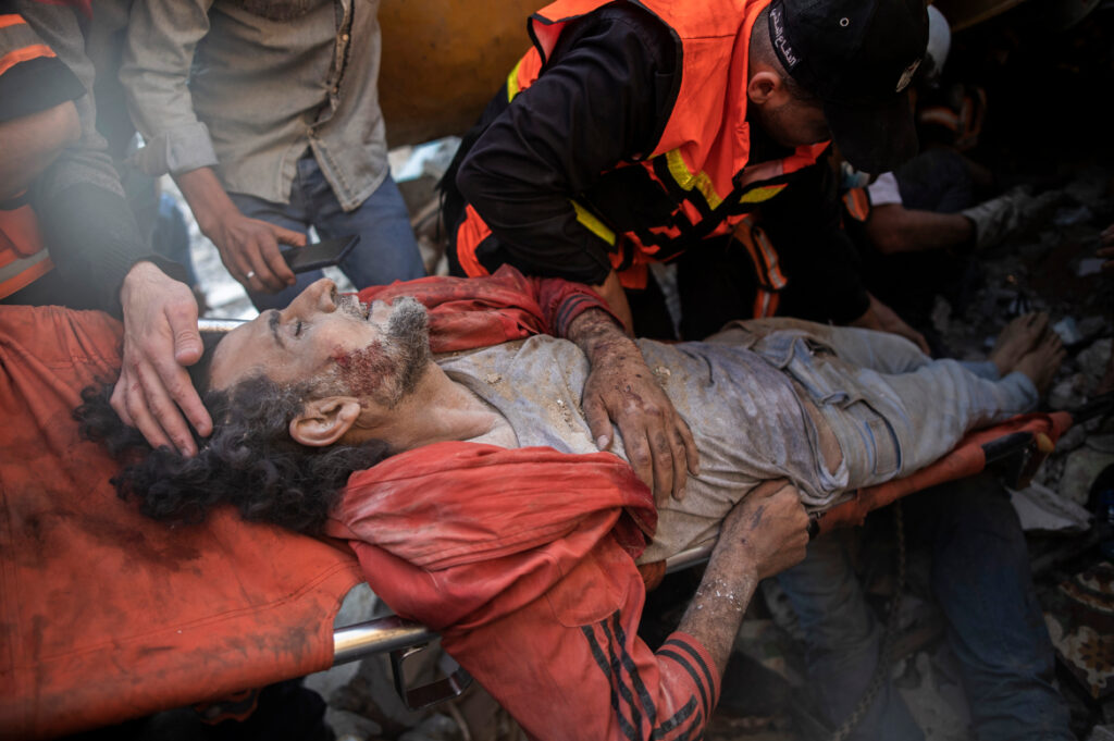 Palestinian rescuers pull a survivor from under the rubble of a destroyed residential building following deadly Israeli airstrikes in Gaza City, Sunday, May 16. The airstrikes flattened three buildings and killed at least 26 people Sunday, medics said, making it the deadliest single attack since the assault began last week. Photo: Khalil Hamra/AP
