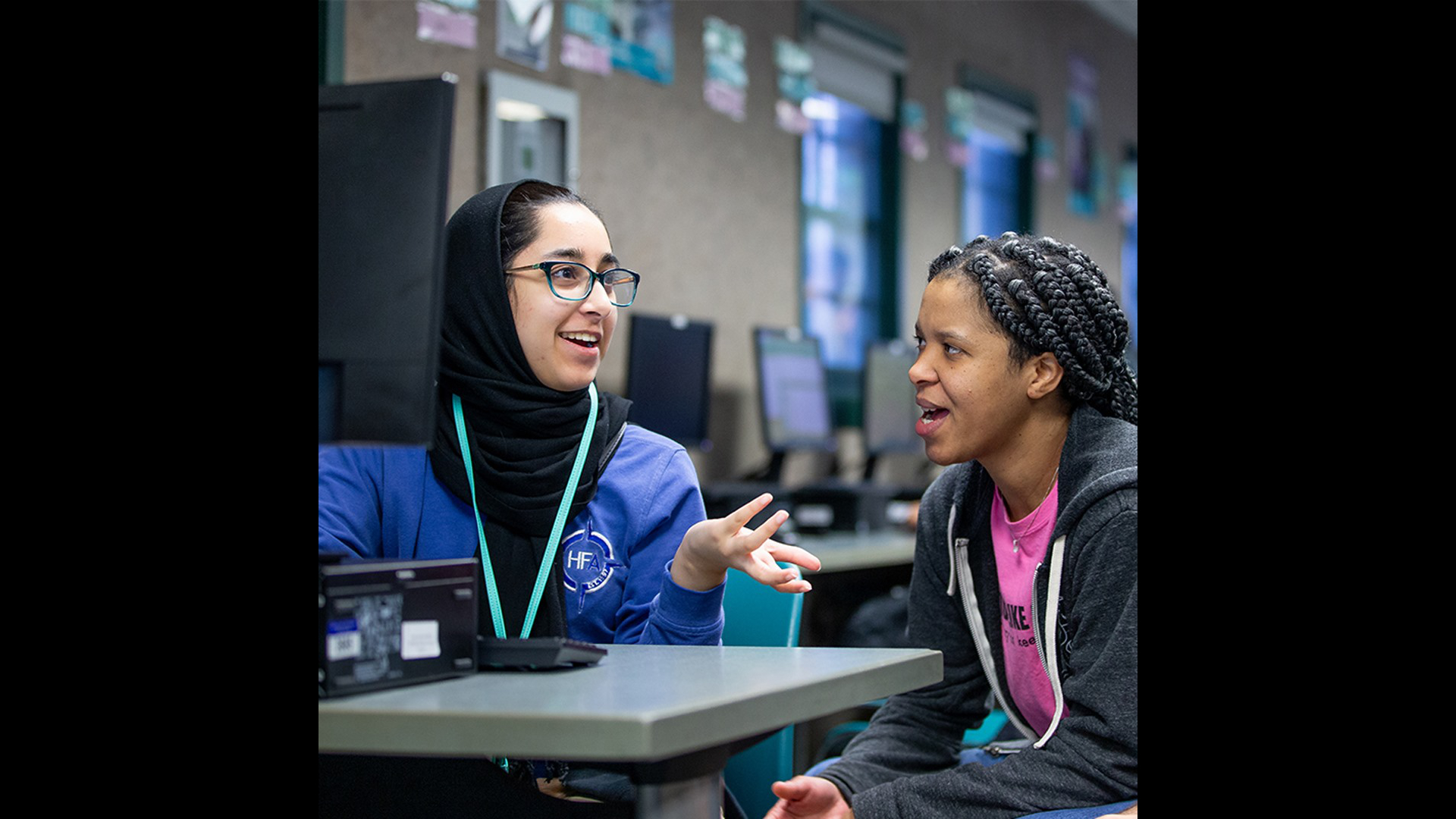 A student in hijab learns tech from an instructor