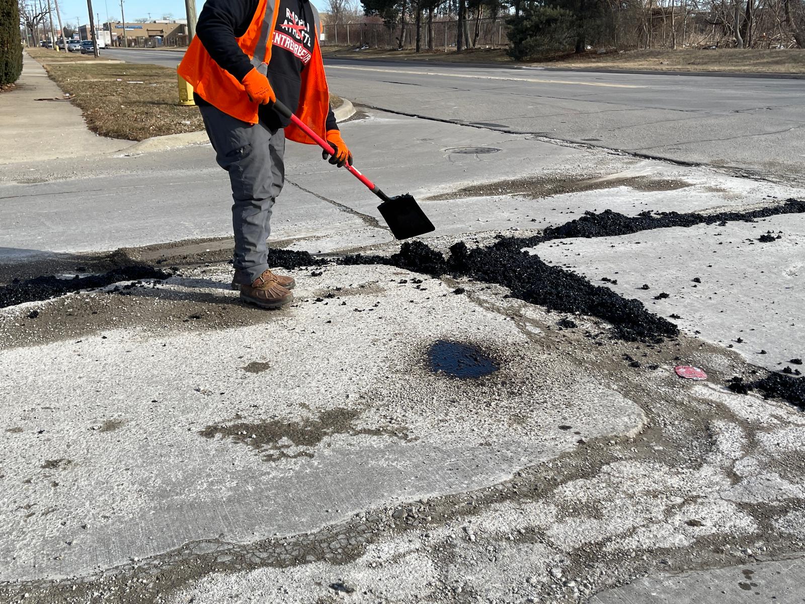 A city of Dearborn road maintenance worker fills out damaged segments Miller Road, Thursday, March 3. Photo: Imad Mohamad/The Arab American News