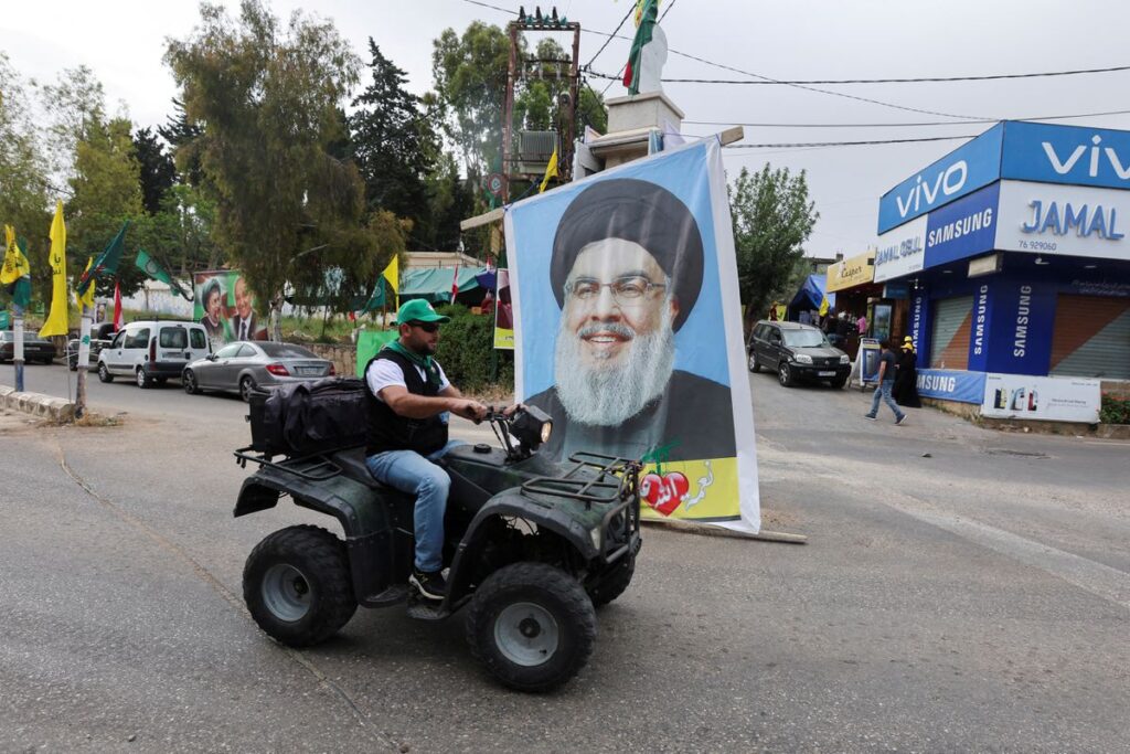 A supporter of the Amal Movement drives past a poster of Lebanon's Hezbollah leader Sayyed Hassan Nasrallah on the parliamentary election day in Houla, southern Lebanon, May 15. Photo: Reuters