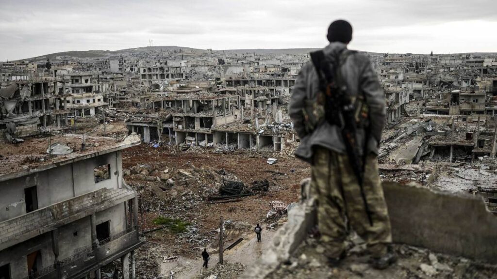 A man stands atop a building looking at the destroyed Syrian town of Kobane, also known as Ain al-Arab, 2015. – File photo